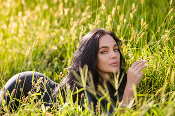 Sexy woman lying on grass. Summer beauty sexy woman outdoor portrait. Beautiful woman relaxing in the field with green grass.