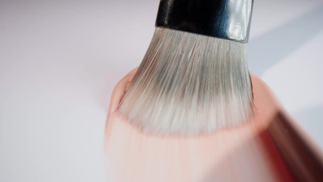 A brush that spreads base make-up in fluid on white surface