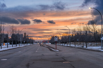 Sunset landscape in city of Edmonton with light snow cover and red and yellow traffic lights