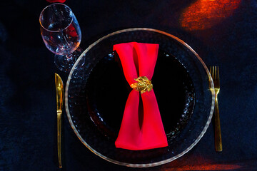A black plate with a red napkin with a gold ring. 