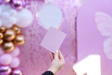 female hand with a sheet of paper on the background of the Beautiful decor