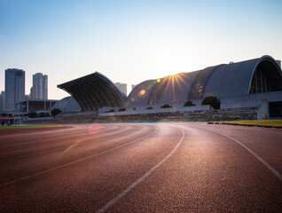 In the city, sunlight shines on outdoor sports stadiums, and outside the stadiums are towering...