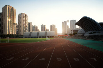 In the city, sunlight shines on outdoor sports stadiums, and outside the stadiums are towering...