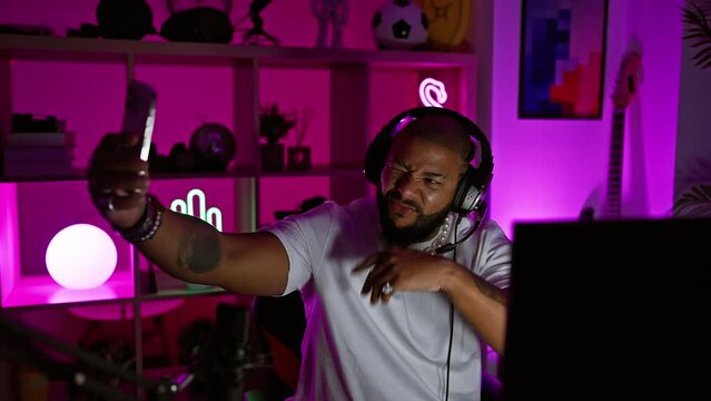 An enthusiastic man with headphones gesturing while gaming in a vibrant, neon-lit room at night.