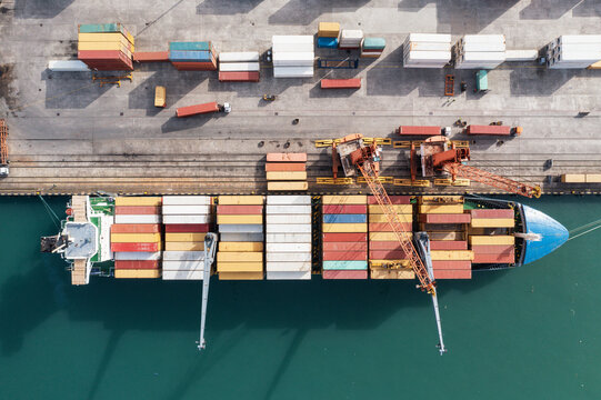 Top down aerial view of cargo ship loading containers. Showcases maritime shipping efficiency. Part of global distribution network.