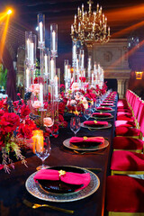 Beautiful festive table setting with fresh red flowers, napkins and candles. 