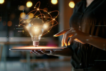 A woman holds a tablet in her hands, on which hovers an innovative concept: a lightbulb generating energy. Abstract. Innovation