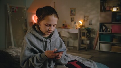 Young beautiful girl uses smartphone, sets up sound in headphones, then talks with friend sitting...