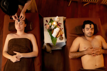 Top view couple enjoying relaxing anti-stress head massage with hot stone and pampering facial...