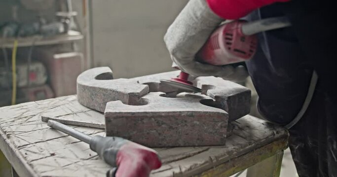 Stoneworker Using Angle Grinder On Granite Stone At Workshop. closeup shot