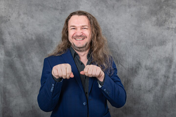 Attractive man with long hair in elegant blue suit poses in various positions