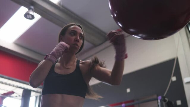 Strong ethnic woman exercising with boxing ball.