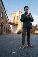 Focused Man Using Smartphone by the Iconic Brooklyn Bridge