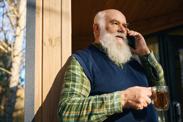 Elderly man communicates on a mobile phone on the veranda