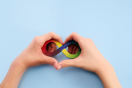 Autistic boy hands and rainbow eight infinity symbol. Autism awareness day symbol.
