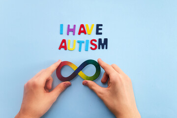 Autistic boy hands and rainbow eight infinity symbol. Autism awareness day symbol.
