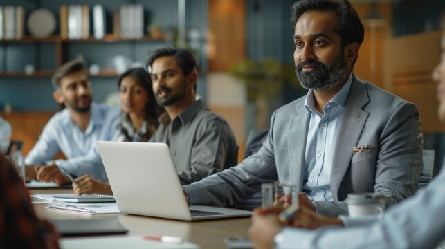 Successful Indian CEO Making a Presentation on a Laptop to a Board of Directors During a Corporate Meeting. South Asian Business Partners Discussing International Markets