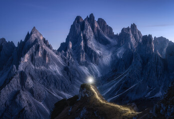 Flashlight trails on mountain path against high rocks at night