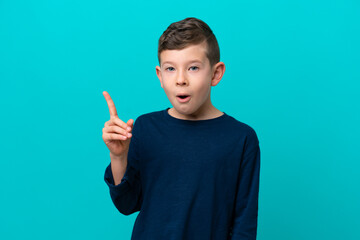 Little kid boy isolated on blue background intending to realizes the solution while lifting a finger up - obrazy, fototapety, plakaty