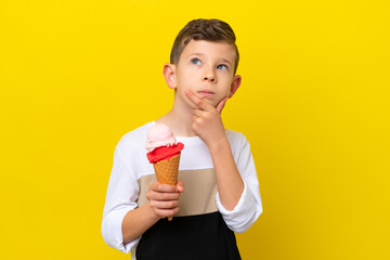 Little caucasian boy with a cornet ice cream isolated on yellow background having doubts