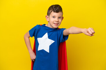 Little caucasian boy isolated on yellow background in superhero costume with proud gesture