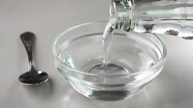 Pouring plain vinegar in a glass bowl.