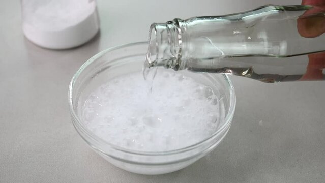 Mixing vinegar with baking soda in glass bowl
