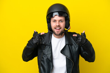 Young caucasian man with a motorcycle helmet isolated on yellow background giving a thumbs up gesture