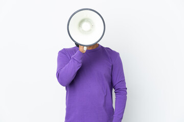 Young Ecuadorian man isolated on white background shouting through a megaphone to announce something