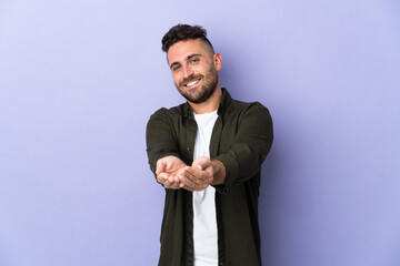 Caucasian man isolated on purple background holding copyspace imaginary on the palm to insert an ad