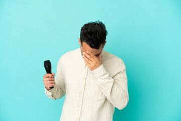 Young caucasian singer man isolated on blue background with tired and sick expression