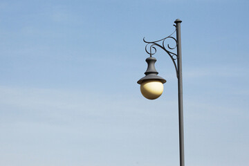 Victorian street light. Street lamp isolated on blue sky. Black paint metal construction....