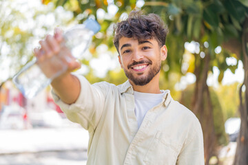Young Arabian handsome man with a bottle of water at outdoors