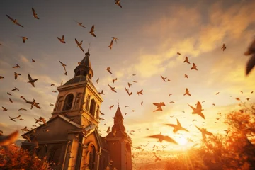Foto op Canvas A church steeple illuminated by a golden sunset and surrounded by birds in flight © Michael Böhm