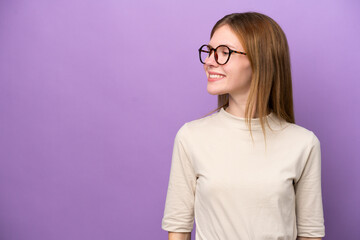 Young English woman isolated on purple background looking to the side and smiling