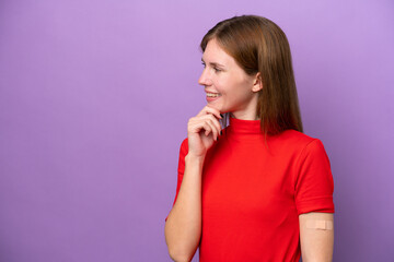 Young English woman wearing band-aids isolated on purple background thinking an idea and looking side