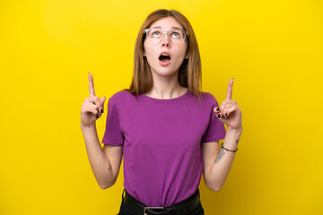 Young English woman isolated on yellow background surprised and pointing up - obrazy, fototapety, plakaty