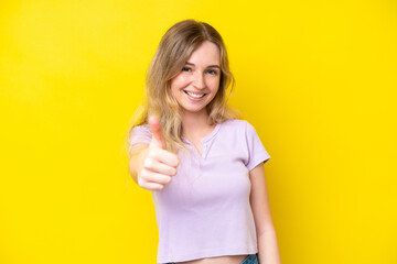 Blonde English young girl isolated on yellow background with thumbs up because something good has happened