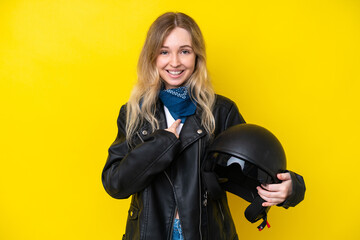 Blonde English young girl with a motorcycle helmet isolated on yellow background with surprise...