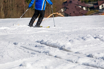 skier in a blue jacket sets off from a snowy slope on a sunny day. Active family vacation