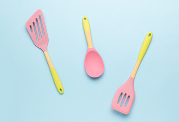 Yellow and pink silicone kitchen spatulas on a blue background.
