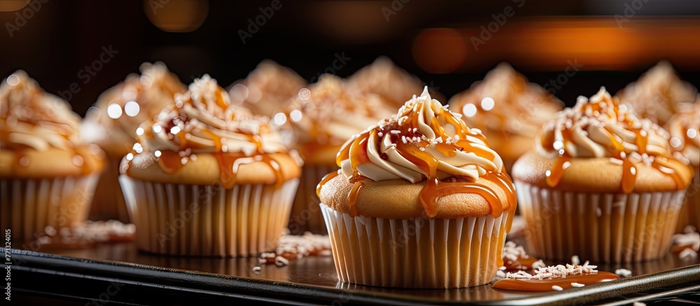 Poster assorted caramel cupcakes decorated with colorful sprinkles arranged neatly on a baking tray