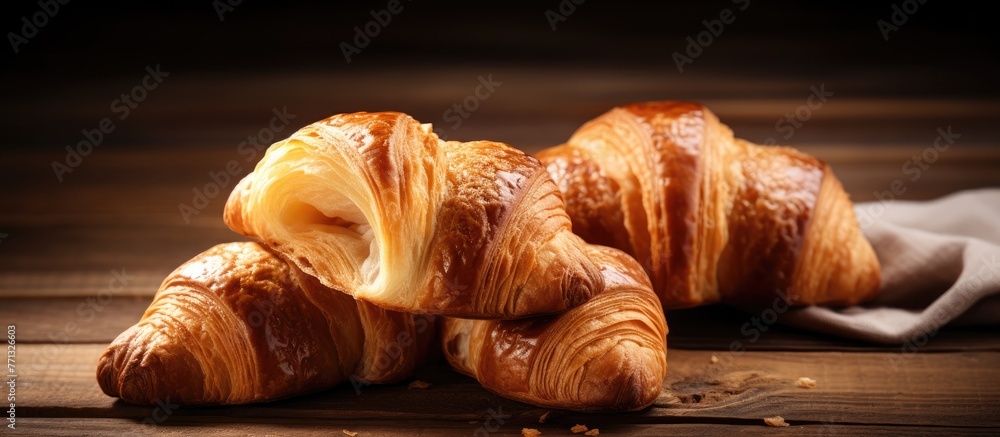 Poster two delicious croissants are displayed on a rustic wooden table accompanied by a white napkin