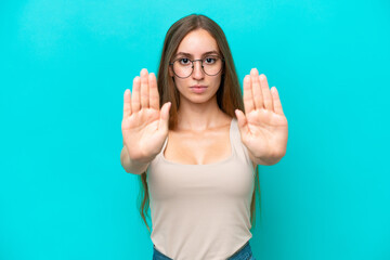 Young caucasian woman isolated on blue background making stop gesture and disappointed