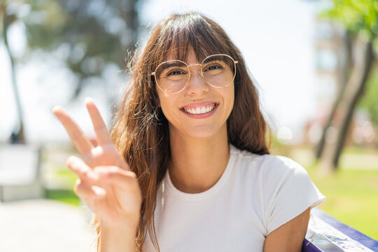 Young woman at outdoors With glasses and doing OK sign