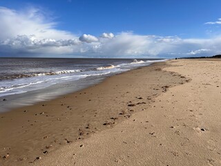 Beautiful sandy beach landscape with sand dunes and low sea tide stream water under blue sky with cloud in Spring in Norfolk East Anglis uk