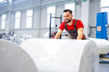 Plakaty  Working in cellulose factory pushing rolls of new paper.