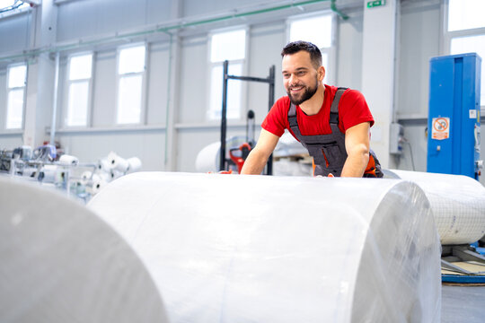 Working in cellulose factory pushing rolls of new paper.