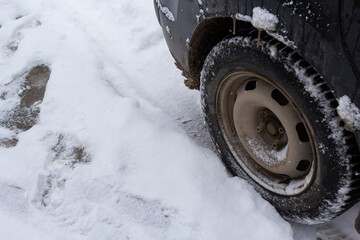 Traffic on winter road after heavy snow. Close up of winter tire on the car on snowy road in town