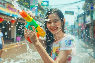 Foto op Plexiglas Happy traveler asian woman wearing summer shirt holding colourful squirt water gun over blur city, Water festival holiday concept © grapestock